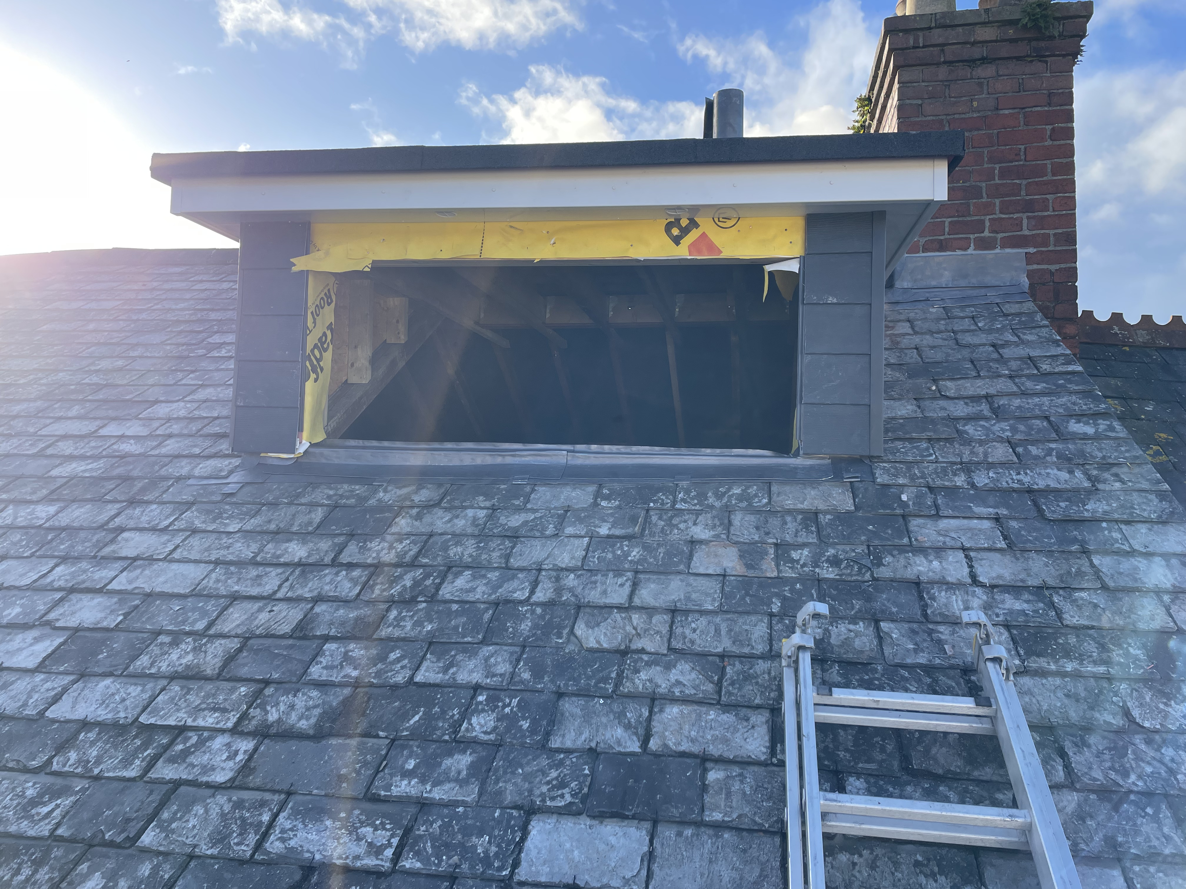 New dormer window construction on a pitched roof in Totnes, showcasing modern composite cladding integration with heritage reclaimed Delabole natural slate and Code 4 lead flashing.