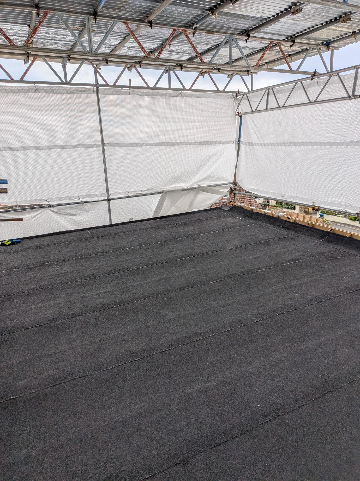 Wide view of near-complete high-performance SBS torch-on flat roof replacement in Ipplepen under temporary scaffold cover