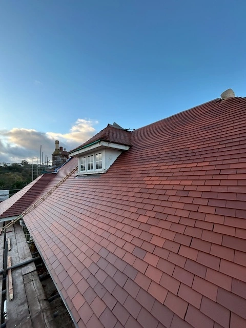 A wide panoramic shot of a completed roof in Torbay under a clear blue sky.