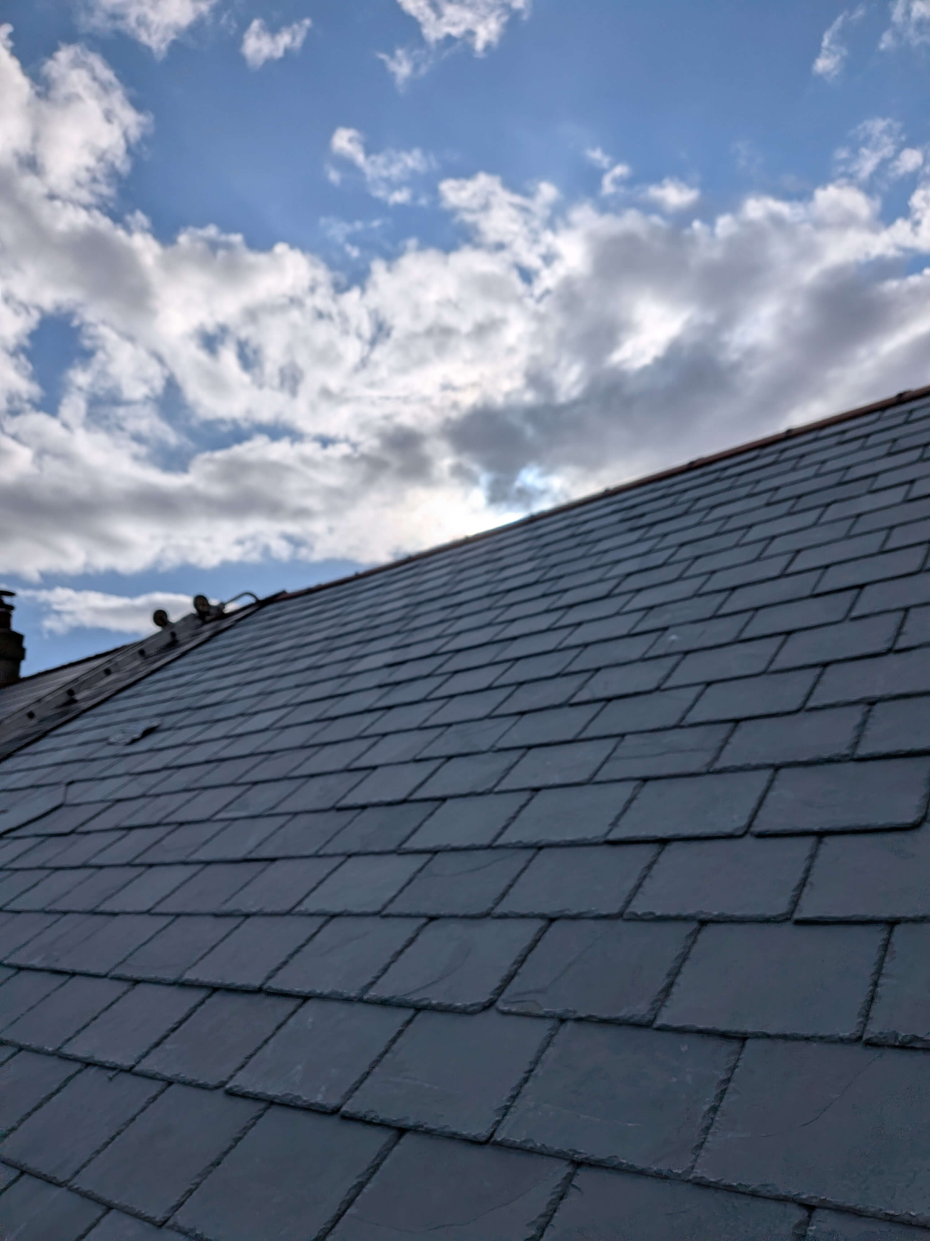 High-performance natural slate roofing installation against the Devon skyline, showing perfect alignment and breathable membrane integration in Brixham TQ5.