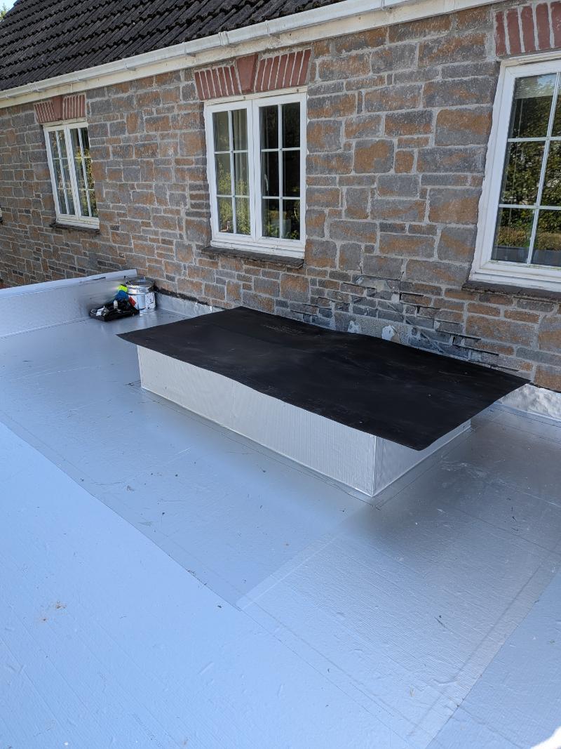 Alutrix vapour control layer dressed against natural stone external house wall and raised skylight kerb